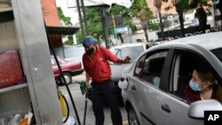 Un trabajador con mascarilla trabaja llenando el tanque de gasolina de una cliente en una estación de servicio de la petrolera estatal PDVSA en Caracas, Venezuela. Mayo 25, 2020