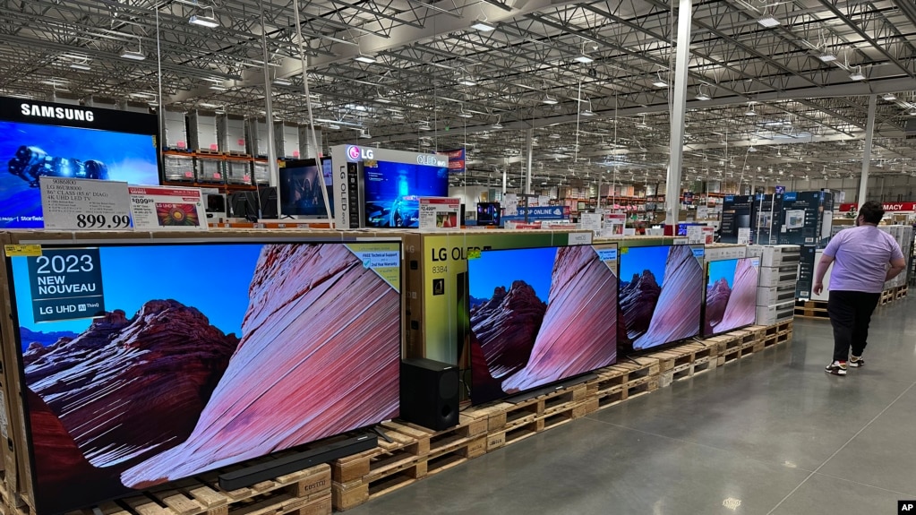 FILE - A shopper passes by a line of large-screen televisions on display in a Costco warehouse, Feb. 3, 2025, in east Denver. Flat screen TVs are the ancestor of the first televisions developed by Farnsworth. (AP Photo/David Zalubowski)