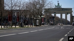 FILE - An almost empty road leads towards the Brandenburg Gate in Berlin, Germany, March 24, 2020.