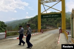 FILE - Myanmar police survey a bridge in Myanmar's Chin state, near the border with India where huge quantities of Indian-made pseudoephedrine, the main ingredient for methamphetamine is smuggled into Myanmar, May 10, 2016.