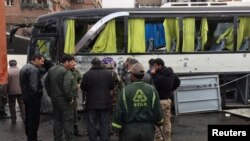 Syrian army soldiers and civilians inspect the damage at the site of an attack by two suicide bombers in Damascus, Syria, March 11, 2017. 