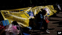 A woman holds a photo of her husband, a Ukrainian soldier, during a gathering in support of soldiers who defended Mariupol and are still in Russian captivity after two and half years, in Kyiv, Ukraine, Oct. 9, 2024.