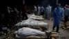 A health worker wearing personal protective equipment (PPE) walks past the funeral pyres of those who died from the COVID-19 during a mass cremation at a crematorium in New Delhi, India, April 26, 2021.