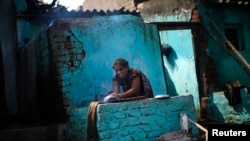 FILE - A woman cooks food outside her partially damaged house at the cyclone-hit Gopalpur village, in Ganjam district in the eastern Indian state of Odisha, Oct. 14, 2013.