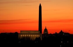 FILE - The sky turns shades of red as the sun rises behind the U.S. Capitol, the Washington Monument and the Lincoln Memorial in Washington, November 19, 2020.