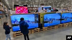 FILE - Young shoppers look over a row of large-screen televisions on display in a Costco warehouse Dec. 19, 2024, in Denver. 