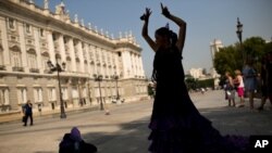 ARCHIVO - Una bailaora de flamenco, con su tradicional vestido, baila frente al Palacio Real en Madrid.