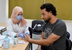 An employee of the Tunisian Health ministry takes a blood sample to test a teacher against the COVID-19 in a school of Tunis, Wednesday, May 27, 2020.