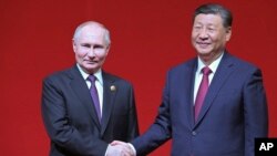 Presiden Rusia Vladimir Putin dan Presiden China Xi Jinping berjabat tangan saat konser memperingati 75 tahun hubungan diplomatik antara Rusia dan China serta pembukaan Tahun Kebudayaan China-Rusia di Pusat Seni Pertunjukan Nasional di Beijing, China, 16 Mei 2024. (Foto: via AP)