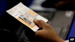 FILE - An election official checks a voter's photo identification at an early voting polling site in Austin, Texas, Feb. 26, 2014.