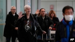 Philadelphia Orchestra's 73-year-old violinist Davyd Booth, second left, waves as he walks ahead of our members upon arriving at the Beijing Capital International Airport on Tuesday, Nov. 7, 2023. (AP Photo/Ng Han Guan)