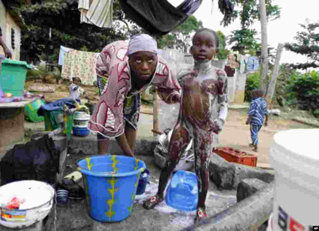 A Gabonese woman showers her daughter at the door of her house in Franceville, south of Libreville January 21, 2012.