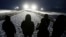 Military veterans stand on a bridge across from police protecting the Dakota Access oil pipeline site in Cannon Ball, N.D., Dec. 1, 2016.