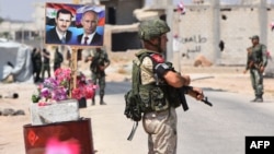 Members of Russian and Syrian forces stand guard near posters of Syrian President Bashar al-Assad and his Russian counterpart Vladimir Putin at the Abu Duhur crossing on the eastern edge of Idlib province, Aug. 20, 2018.