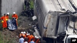 Rescuers carry a body of a victim discovered among the wreckage after two carriages from a bullet train derailed and fell off a bridge in Wenzhou, Zhejiang province, China, July 24, 2011