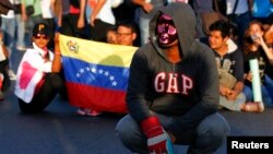 Un manifestante usando una máscara bloquea una calle durante una protesta contra el gobierno de Nicolás Maduro, en Caracas.