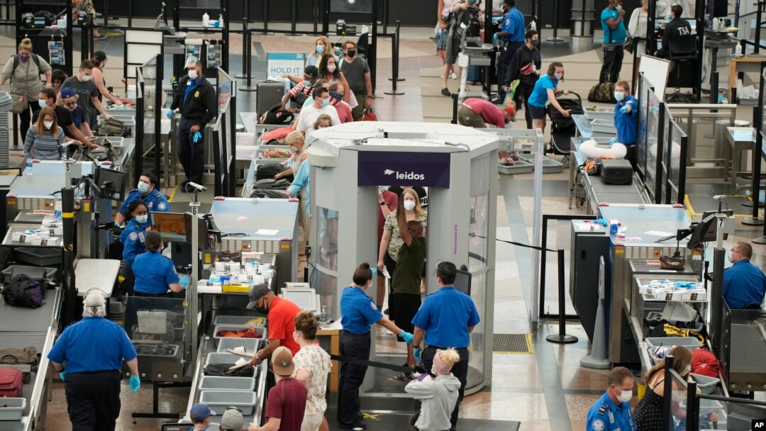FILE - Travelers wear face coverings in the line for the south security checkpoint in the main terminal of Denver International Airport on Aug. 24, 2021, in Denver.