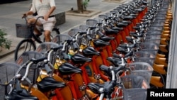 FILE - A man rides past a station with bicycles of Youbike, a bicycle-sharing system, in Taipei, Taiwan, Aug. 31, 2017. 