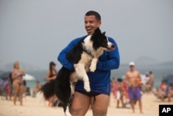 Coach Gustavo Rodrigues celebrates a point with his trainee, border collie named Floki, as they play footvolley, a combination of soccer and volleyball, on Leblon beach in Rio de Janeiro, Sunday, Sept. 8, 2024. (AP Photo/Bruna Prado)