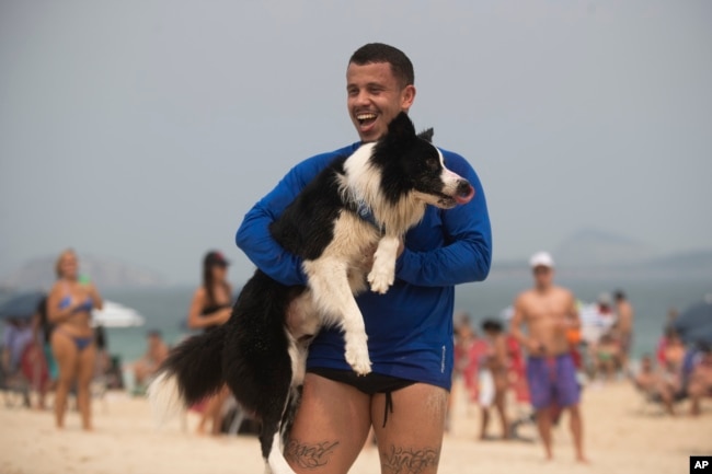 Coach Gustavo Rodrigues celebrates a point with his trainee, border collie named Floki, as they play footvolley, a combination of soccer and volleyball, on Leblon beach in Rio de Janeiro, Sunday, Sept. 8, 2024. (AP Photo/Bruna Prado)