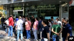 People line up in front of a currency exchange shop to buy U.S. dollars and euros, in downtown Tehran, Iran, Sept. 5, 2018. The Iranian rial fell Wednesday to its lowest rate on record and saw worried residents of Tehran line up outside of beleaguered moneychangers, part of a staggering 140-percent drop in the currency's value since America pulled out of the nuclear deal four months ago.