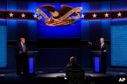 FILE - President Donald Trump, left, Democratic presidential candidate former Vice President Joe Biden, right, during the first presidential debate with moderator Chris Wallace of Fox News, center, Sept. 29, 2020, in Cleveland, Ohio.