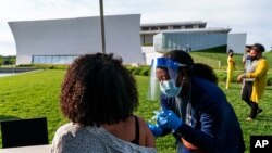 FILE - Kendria Brown, a nurse with DC Health, vaccinates a woman against COVID-19, May 6, 2021, near the Kennedy Center in Washington. 