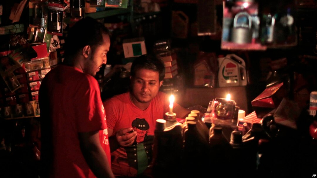 A Bangladeshi salesman interacts with a customer during a blackout in Dhaka, Bangladesh, Nov. 1, 2014.
