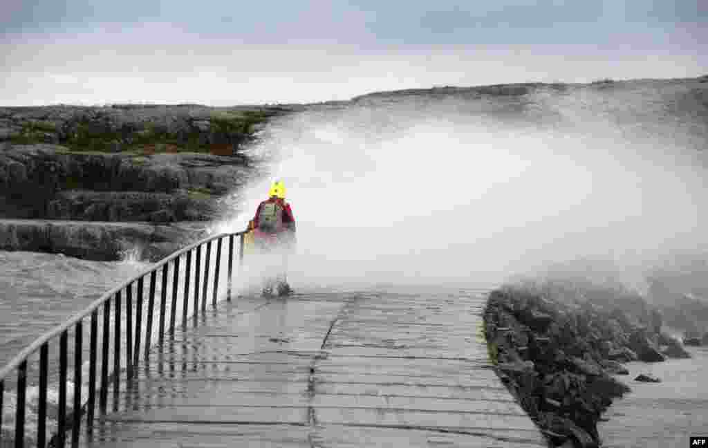 A woman is hit by a wave caused by stormy winds in Helsinki, Finland.