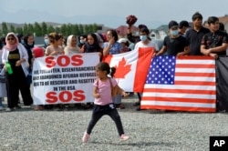 Afghan migrants take part in a rally outside the U.S. Embassy in Bishkek, Kyrgyzstan, Aug. 19, 2021, requesting Kyrgyz citizenship or resettlement to the U.S. or Canada.