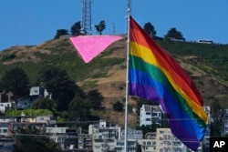 FILE - A pink triangle is seen on top of Twin Peaks behind the Castro district rainbow flag in San Francisco, June 20, 2023.