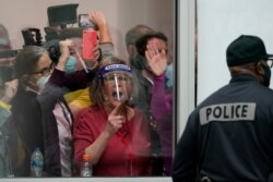 FILE - In this Nov. 4, 2020, file photo, election challengers yell as they look through the windows of the central counting board as police were helping to keep additional challengers from entering due to overcrowding, in Detroit.