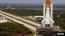 FILE - Space Shuttle Discovery, resting on the Mobile Launcher Platform, turns the corner on the crawlerway as it rolls back from Launch Pad 39B to the Vehicle Assembly Building, March 26, 2005. (Image Credit: NASA/KSC)