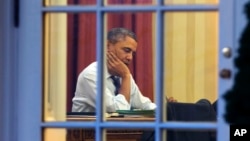 President Barack Obama works at his desk in the Oval Office of the White House in Washington, Jan. 27, 2014, ahead of Tuesday night's State of the Union speech.