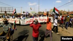 FILE - Protesters carry a banner and national flags as they march against the Sudanese military's recent seizure of power and ousting of the civilian government, in the streets of the capital Khartoum, Sudan, Oct. 30, 2021.