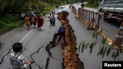 Warga di Chiang Rai, bagian utara Thailand, melintasi jalanan yang rusak akibat gempa (6/5). Gempa bumi berkekuatan 6SR mengguncang wilayah ini hari Senin, 5 Mei 2014.