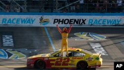 Driver Joey Logano stands on his race car at the start-finish line as he celebrates after winning the NASCAR Cup Series auto race at Phoenix Raceway, Sunday, March 8, 2020, in Avondale, Ariz. (AP Photo/Ralph Freso)