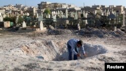 A man inspects a hole in the ground after what activists said was an airstrike by forces loyal to Syria's President Bashar al-Assad in Khan Sheikhoun, northern Idlib province, Dec. 26, 2014. 