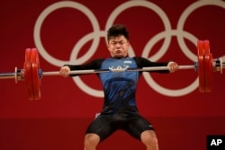 FILE - Igor Son of Kazakhstan competes in the men's 61 kilogram weightlifting event at the 2020 Summer Olympics, July 25, 2021, in Tokyo, Japan. Son, who won the bronze in the category, was among six weightlifters from Kazakhstan to receive doping bans.