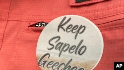 FILE - A sticker saying "Keep Sapelo Geechee" is worn on the shirt of George Grovner, a resident of the Hogg Hummock community on Sapelo Island, during a meeting of McIntosh County commissioners, September 12, 2023, in Darien, Ga.