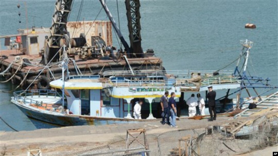 Petugas kepolisian menginspeksi kapal yang ditarik ke pelabuhan Catania, selatan Italia (10/8). Kapal ini dilaporkan mengangkut sedikitnya 100 imigran sebelum kandas di lepas pantai Italia.