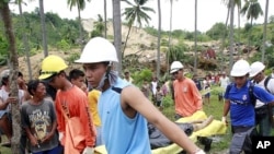 Rescuers carry a body retrieved from a landslide caused by an earthquake in La Libertad, Negros Oriental in central Philippines February 7, 2012.