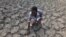 FILE - Last Zimaniwa feels the broken ground at a spot which is usually a reliable water source that has dried up due to lack of rains in the village of Chivi , Zimbabwe, Jan. 29, 2016. Southern Africa's lengthy drought has gotten worse, aid officials say