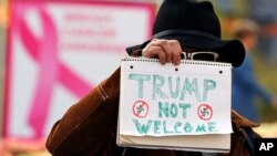 A man holds a sign outside the University of Pittsburgh's Presbyterian Hospital before the arrival of President Donald Trump's motorcade in Pittsburgh, Oct. 30, 2018. 