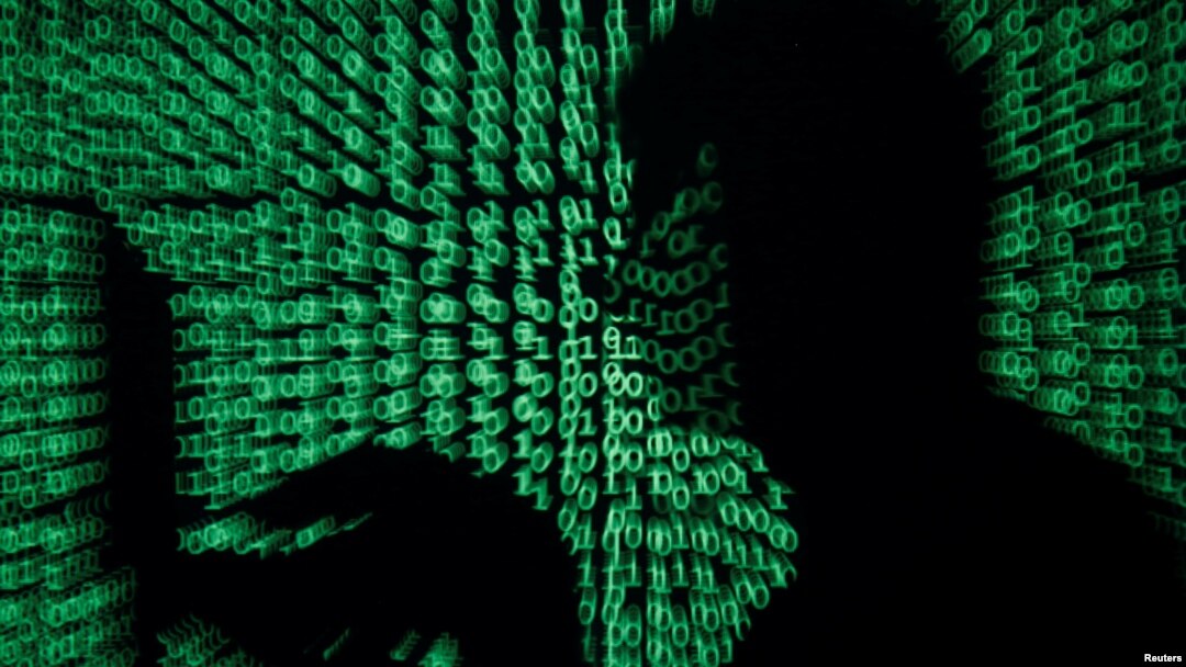 A man holds a laptop computer as code is projected on him in this illustration made on May 13, 2017. 