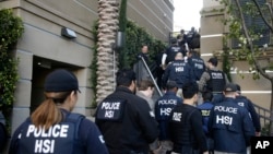 FILE - Federal agents enter an upscale apartment complex where authorities say a birth tourism business charged pregnant women $50,000 for lodging, food and transportation, in Irvine, California, March 3, 2015.