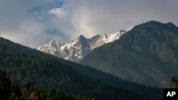 Awan hujan terlihat di atas beberapa puncak pegunungan Dhauladhar Himalaya di Dharmsala, India, Minggu, 7 Juni 2020. Seorang pendaki gunung AS dan pemandunya yang berasal dari Nepal tewas dalam bencana longsoran salju di Gunung Shishapangma di Tibet. (Foto: AP)