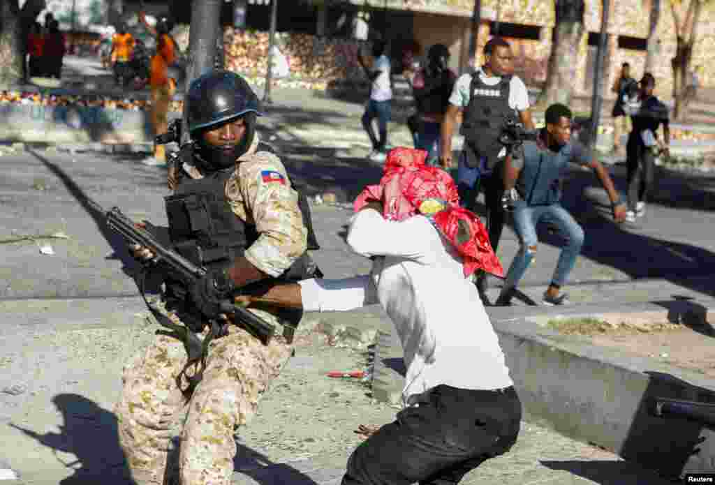 A demonstrator tries to take the gun of a police officer during protests against Haiti&#39;s President Jovenel Moise, in Port-au-Prince, Feb. 8, 2021.