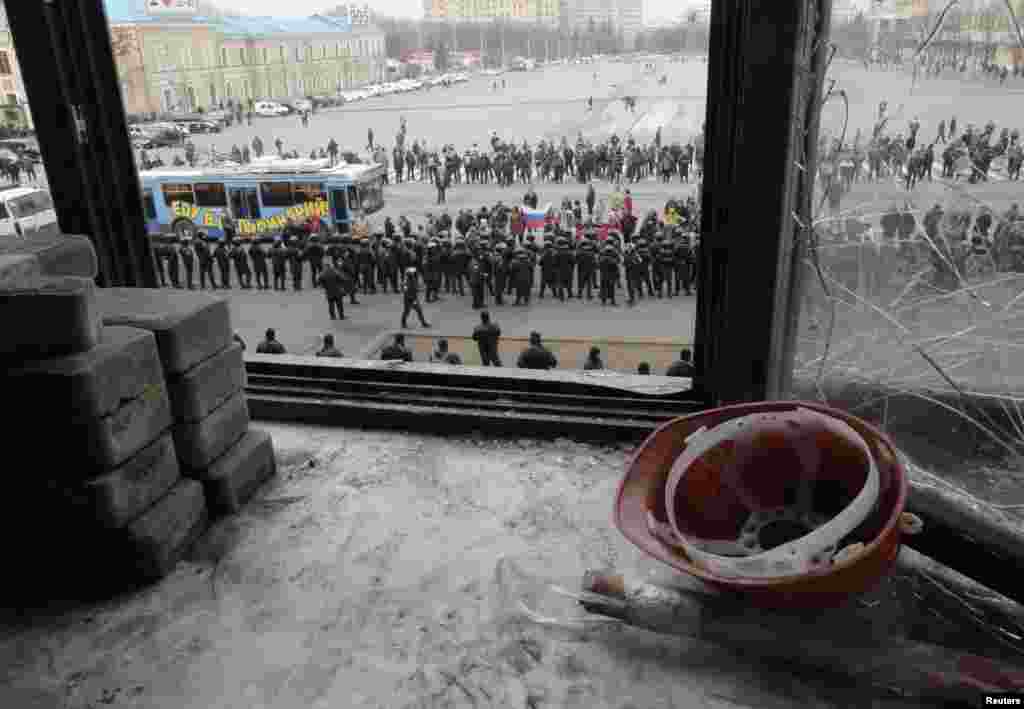 A view through a broken window of the regional administration building shows a cordon of Interior Ministry members blocking a group of pro-Russian protesters in Kharkiv, Ukraine, April 8, 2014.