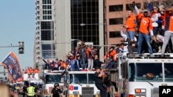 Members of the Denver Broncos wave to adoring fans from atop a fleet of firetrucks during a Super Bowl victory parade in Denver, Feb. 9, 2016.